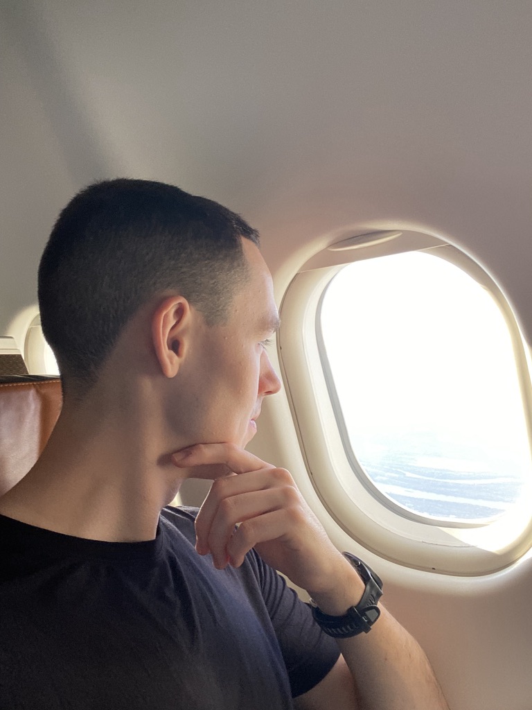 Victor looking out an airplane window, chin resting on his hand.